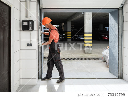 Worker is checking with the water level the vertical guide of the lift gate. Worker is checking with the water level the vertical guide of the lift gate. 73319799