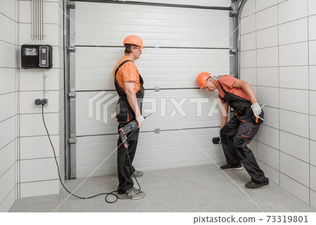 Workers are installing lift gates in the garage. 73319801