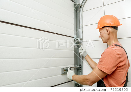 Worker is installing lift gates in the garage. Worker is installing lift gates in the garage. 73319803