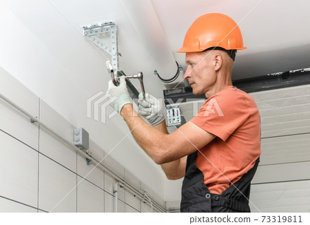 The worker is installing lift gates in the garage. 73319811