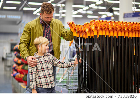 handsome man with son choosing shovel for the garden 73319820