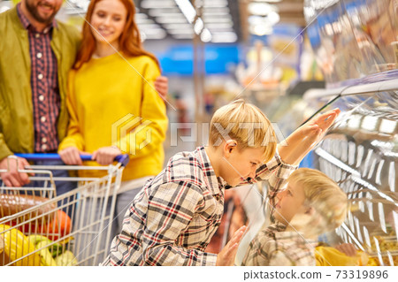 funny child boy leaned on showcase in supermarket 73319896
