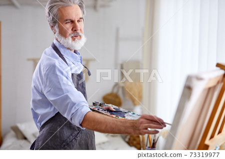 senior artist holding creating masterpiece using paintbrush, stand near canvas senior artist holding creating masterpiece using paintbrush, stand near canvas 73319977