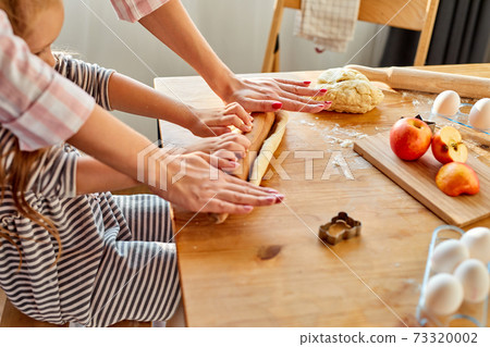 caring mommy helping cute smiling little preschool child daughter rolling dough for homemade cookies 73320002