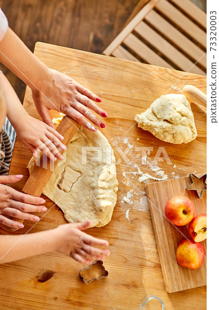 cropped mother teaches daughter prepare dough in the kitchen with fun 73320003