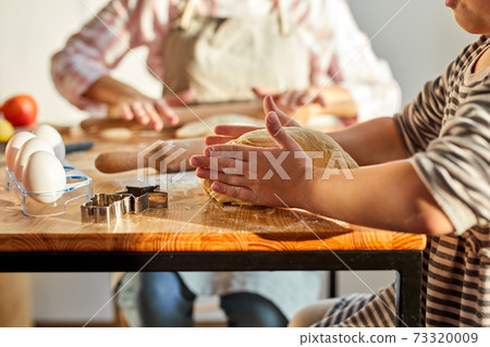 caucasian mother and daughter kneading dough for homemade dessert in kitchen 73320009