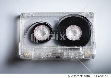 Close-up of a classic audio cassette tape with magnetic tape inside. Retro background Close-up of a classic audio cassette tape with magnetic tape inside. Retro background 73320345