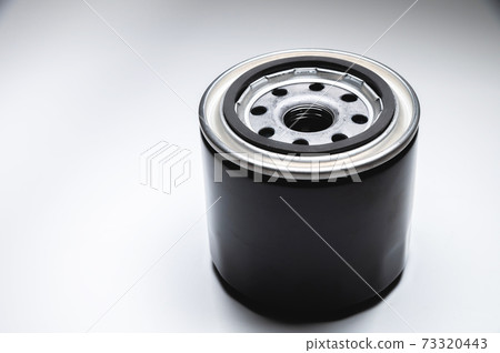 Black new oil filter in contrasting light on a black and white background. Wide angle Black new oil filter in contrasting light on a black and white background. Wide angle 73320443
