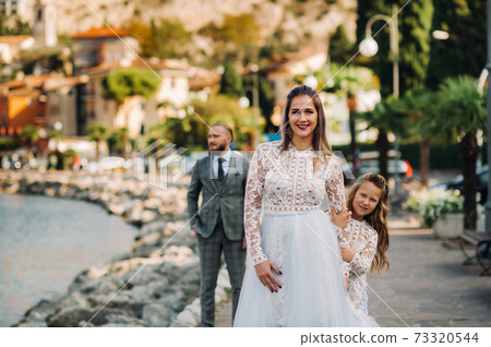 Italy, Lake Garda. Beautiful family on the shores of lake Garda in Italy at the foot of the Alps. Father, mother and daughter in Italy Italy, Lake Garda. Beautiful family on the shores of lake Garda in Italy at the foot of the Alps. Father, mother and daughter in Italy 73320544