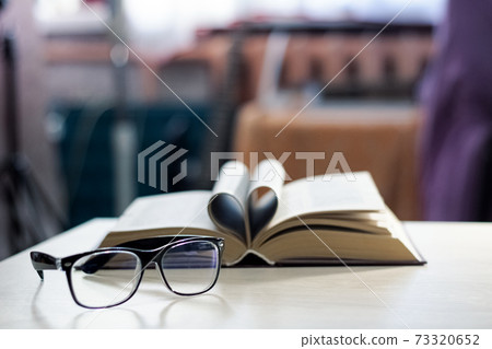 Black glasses on the background of the book in the light of the sun Black glasses on the background of the book in the light of the sun 73320652