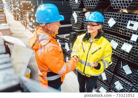 Customer and worker in steel delivery warehouse shaking hands 73321052