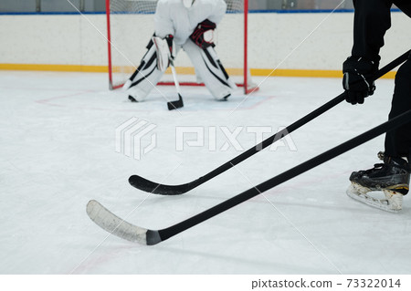 Hockey sticks held by two players in sports uniform on background of goal keeper Hockey sticks held by two players in sports uniform on background of goal keeper 73322014