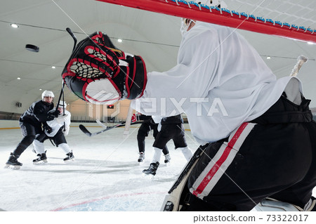 Back view of hockey player in sports uniform and gloves standing in the net Back view of hockey player in sports uniform and gloves standing in the net 73322017