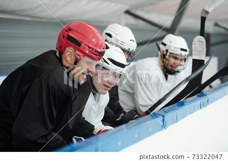 Group of hockey players in sports uniform listening to their experienced trainer 73322047