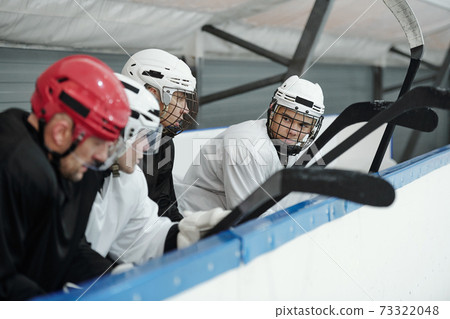 Group of young hockey players in sports uniform and helmets preparing for play 73322048