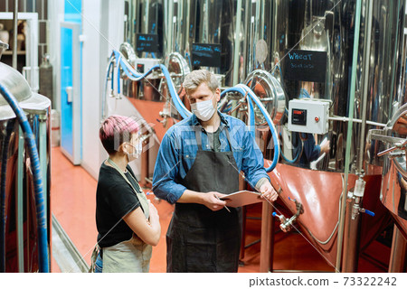 Two young brewers of beer production factory consulting about working moments Two young brewers of beer production factory consulting about working moments 73322242