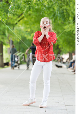 Getting a shocking surprise. Surprised small child with adorable stylish look. Little girl with long blond hair in stylish wear. Stylish kid playing in summer park. Her wardrobe is stylish yet casual 73322527