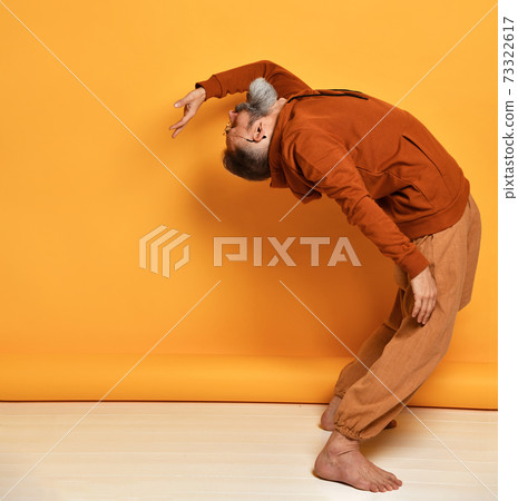 Strong bearded man bending backwards studio shot Strong bearded man bending backwards studio shot 73322617