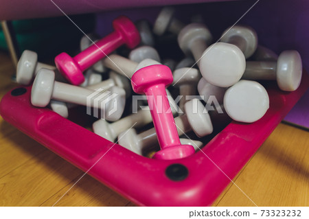 Bright pink, green, red and yellow small dumbbells on a black background. Sport concept. 73323232
