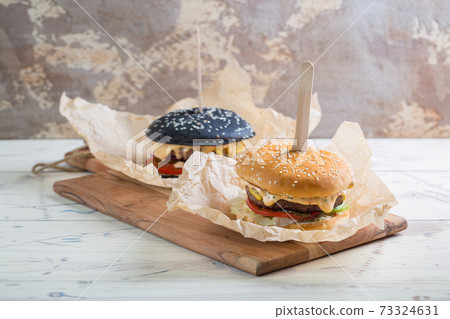 Two homemade beef burgers with greens, red onion, tomatoes, pickled cucumbers and cheese 73324631