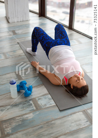 Photo of a middle aged woman during home workout. Vertical photo. Photo of a middle aged woman during home workout. Vertical photo. 73325141