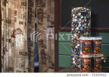Defocused beer bottle caps in a decorative vase, interior of pub Defocused beer bottle caps in a decorative vase, interior of pub 73325412