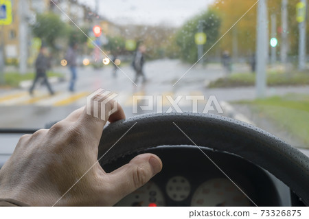 driver's hand on the steering wheel of the car in cloudy weather driver's hand on the steering wheel of the car in cloudy weather 73326875