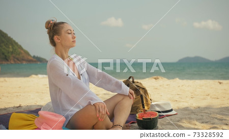 The cheerful woman in holding and eating slices of watermelon on tropical sand beach sea. Portrait attractive girl spend summer weekend. 73328592