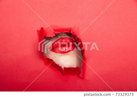 Woman with red lips through torn paper Woman with red lips through torn paper 73329373