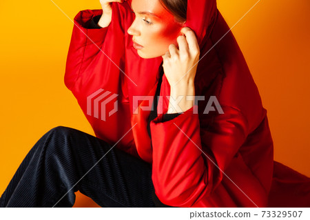 Lonely woman wrapping in baggy coat against yellow background Lonely woman wrapping in baggy coat against yellow background 73329507