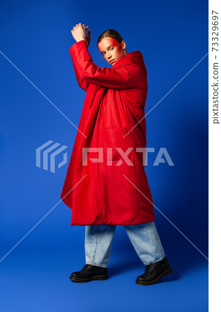 Trendy female dancing on tiptoes against blue background 73329697