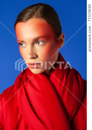 Young model with creative makeup against blue background 73329699