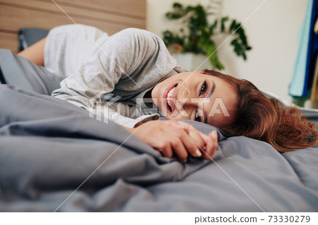 Woman relaxing on comfortable bed Woman relaxing on comfortable bed 73330279