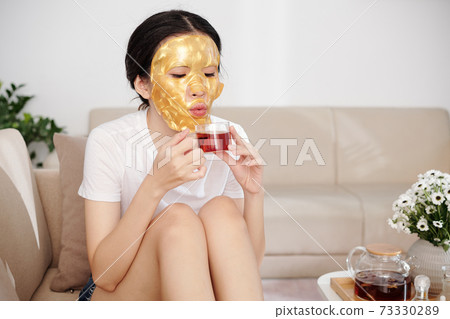Woman with sheet mask on drinking tea Woman with sheet mask on drinking tea 73330289