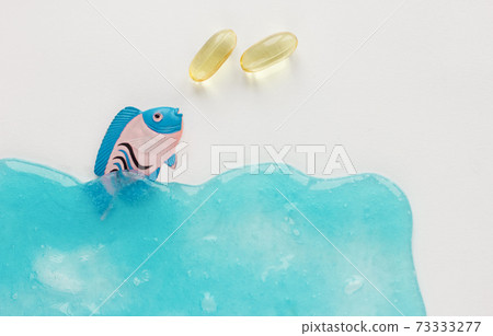 Fish collagen capsules and fish on blue background.  73333277