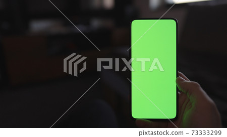 Pov shot of man using phone with green screen indoor in dark lit room Pov shot of man using phone with green screen indoor in dark lit room 73333299
