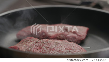 two beef steak pieces frying on nonstick pan two beef steak pieces frying on nonstick pan 73333583