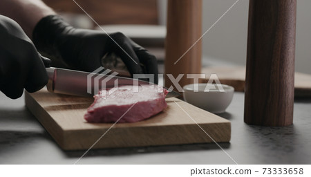 man cut raw beef steak on oak board 73333658