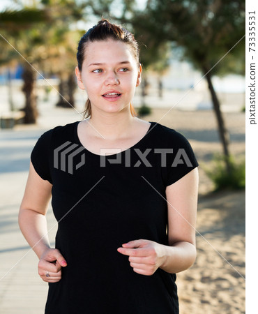 Sportswoman in black T-shirt is jogging Sportswoman in black T-shirt is jogging 73335531