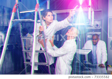 People in white coats are looking for key in a quest room stylized as an laboratory People in white coats are looking for key in a quest room stylized as an laboratory 73335582