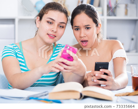 Smiling teenage girls using phones Smiling teenage girls using phones 73335664