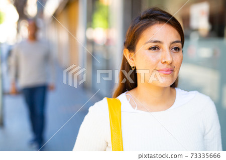 Smiling confident girl standing outdoors with man in background. Smiling confident girl standing outdoors with man in background. 73335666