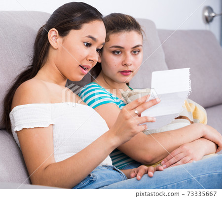 Young girl reading love letter with friend Young girl reading love letter with friend 73335667