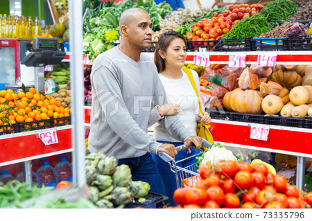 Latin couple choosing vegetables in supermarket together Latin couple choosing vegetables in supermarket together 73335796