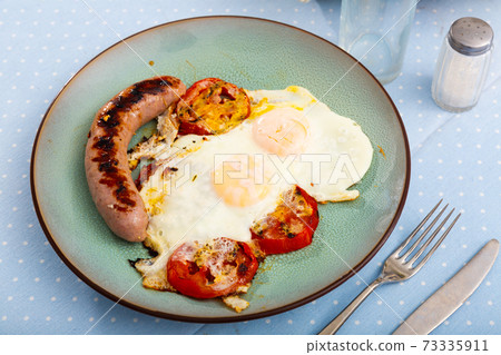 Breakfast with scrambled eggs, sausage and tomatoes 73335911