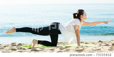 Healthy girl in white T-shirt is practicing yoga Healthy girl in white T-shirt is practicing yoga 73335918