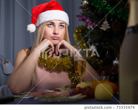 Girl is bored and drinking champagne in New Year night Girl is bored and drinking champagne in New Year night 73335974