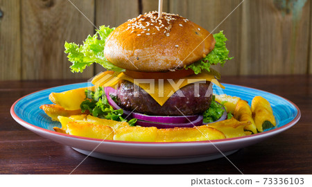 Heeseburger with beef cutlet, fresh vegetables and cheese with french fries 73336103