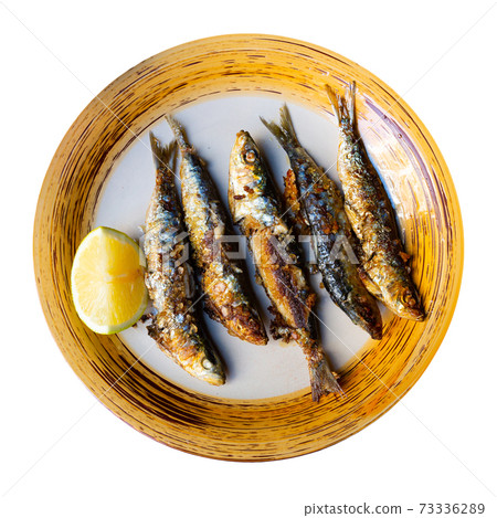 Deliciously fried many sardines served with lemon at plate Deliciously fried many sardines served with lemon at plate 73336289