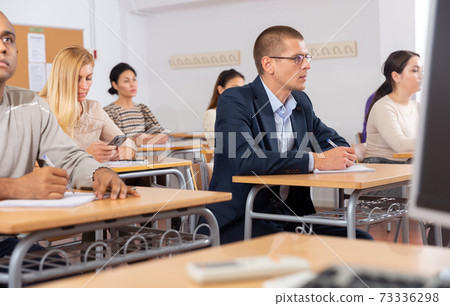 Intelligent adult man in glasses listening to lecture in classroom 73336298